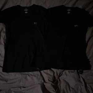 Svarta t-shirts från Armani Exchange - Säljer två stilrena svarta t-shirts från Armani. T-shirten är kortärmad och har en diskret logga på bröstet. Passar bra till både jeans och shorts. Säljs på grund av att det inte är min stil längre. Passformen är slim-fit i storlek S för herr. Båda tröjorna ingår. Skriv för mer info☺️