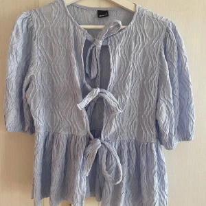 Ljusblå blus med knytband - Säljer en ljusblå blus från Gina Tricot med knytband framtill. Knappt använd!!