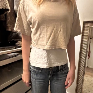 Beige croppad t-shirt och vit underline  - Säljer en beige croppad t-shirt med korta ärmar. Perfekt för en avslappnad stil och kan enkelt matchas med jeans eller kjol.