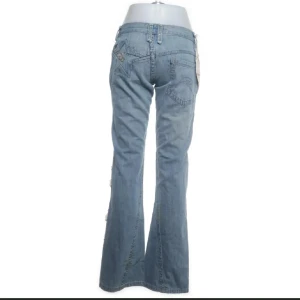 Blå bootcut jeans med - Blå lågmidjade bootcut jeans med en unik styling! Storlek M, passar S med. Säljes då de tyvärr inte alls passade. Köptes för 400kr, säljer för 200kr 