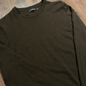 Brun tröja från J.Lindeberg i merinoull  - Säljer en stilren brun tröja från J.Lindeberg. Tröjan har långa ärmar och en enkel design med en liten logotyp på bröstet. Perfekt för en avslappnad och snygg look. Det står storlek M men passar precis som en vanlig S! Tröjan är i mycket bra skick. Nypris 1300kr . Tröjan ser lite grön ut på bilden vilket den inte är i verkligheten. Man ser tydligare på bild 3.