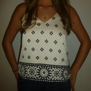 Vit mönstrad linnetopp - Snygg vit linnetopp med blommig kant. 🖤Toppen har smala axelband som korsas super fint i ryggen. Perfekt på sommaren/resor eller på fest🤩