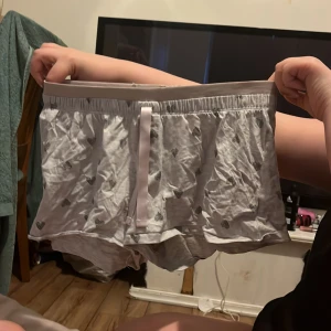 Grå shorts med hjärtmönster - Säljer ett par grå shorts med sött hjärtmönster. De har en bekväm elastisk midja och en liten rosett framtill. Perfekta för en avslappnad dag hemma.