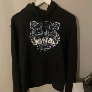 Svart hoodie från Kenzo  - Säljer en svart hoodie från Kenzo med ett coolt tigertryck på framsidan. Storlek M/S. Pris kan diskuteras vid snabb affär!