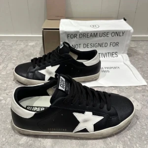 Goolden goose - Skick 9/10 pga använd 1 gång snygga svarta sneakers från Golden Goose med en vit stjärna på sidan. Skorna har en klassisk design med snörning och en vit sula som ger en cool kontrast. Perfekta för en avslappnad stil priset är inte hugget i sten