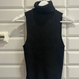 Svart ribbad ärmlös polotröja från SHEIN. Storlek:L - Snygg svart ärmlös polotröja med ribbad design. Perfekt för lager-på-lager eller som ett stilrent basplagg. Polokragen ger en extra touch av elegans. Aldrig använd. Säljer för 70 kronor.✨