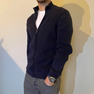 Mörkblå ribbad kofta med dragkedja - Snygg mörblå kofta med dragkedja framtill. Perfekt för lager-på-lager och har en stilren look. Passar bra till både jeans och chinos.