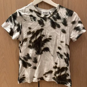 Mönstrad t-shirt från Weekday - Snygg t-shirt från Weekday med ett unikt svart och vitt mönster. Perfekt för en avslappnad stil. Den har en klassisk rund hals och korta ärmar. Använd endast 2 gånger.