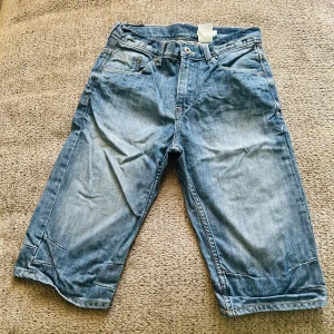 Blå jeansshorts från H&M - Säljer ett par coola blå jeansshorts från H&M. De har en klassisk femficksdesign med knappar och en bekväm passform. Perfekta för en avslappnad stil. 🕶️