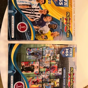 FIFA 365 Adrenalyn XL 2022 Guide och Spelplan - Säljer en FIFA 365 Adrenalyn XL 2022 guidebok och spelplan från Panini. Perfekt för samlare och fotbollsfans som vill ha koll på topplag och spelare. Guideboken har färgglada bilder och detaljerad information. Spelplanen är designad för att spela med samlarkort.