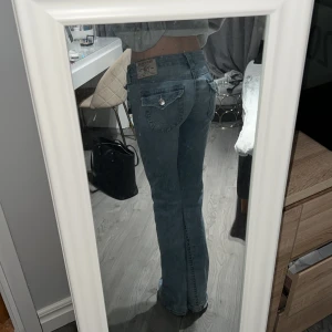 Ljusblå jeans från True Religion - Säljer dessa skit snygga jeans från True Religion i modellen Joey Low Rise Flare. Använda en del i början men bara legat i garderoben i ett par månader nu då de tyvärr blivit förstora för mig. Inga defekter förutom längst ner bak på byxorna så ser man att de gått i marken lite,men absolut inget man tänker på alls då det är så lite. Annars är de superfina övrigt.