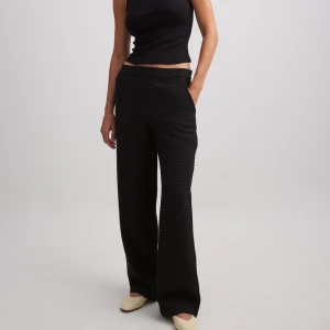 Svarta byxor i tweed - Snygga svarta tweedbyxor med normal passform. Perfekta för en stilren look. Byxorna har en hög midja och är tillverkade i ett bekvämt tweedmaterial.