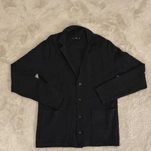 Svart kavaj från MNG - Snygg svart kavaj från MNG med knappar framtill och två praktiska fickor. Passar både män och kvinnor alltså unisex. Perfekt för en stilren look. Tillverkad i ett mjukt material som ger en bekväm passform. Hör av dig vid funderingar och pris kan diskuteras vid snabb affär mvh Malte