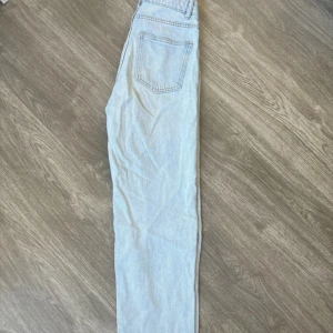 Ljusblå jeansbyxor - Säljer ett par ljusblå jeansbyxor i klassisk stil. De har en rak passform och är perfekta för vardagsbruk. Byxorna har en traditionell femficksdesign och är tillverkade i ett slitstarkt denimtyg. Perfekta för både vår och sommar!