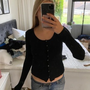 Svart ribbad kofta - Säljer en svart ribbad kofta med knappar framtill. Den är långärmad och har en tight passform, perfekt för både vardag och fest. Koftan är i bra skick och passar till det mesta i garderoben. Perfekt för höst och vår!