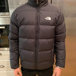 North Face jacka - Svart North Face jacka som kan bäras på två sätt då den är gjord för att kunnas ha både in och ut vändigt. Den är knappt använd så den är in princip i nyskick! Funkar perfekt för både killar och tjejer. Väldigt varm - perfekt för den kalla vintern!