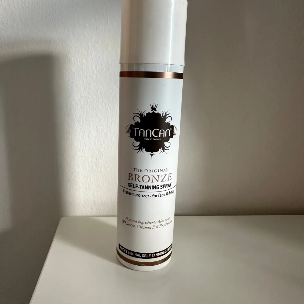 Säljer en TanCan Bronze Self-Tanning Spray för ansikte och kropp. Denna spray ger en naturlig bronzer-effekt och innehåller vårdande ingredienser som Aloe Vera, Vitamin E och Ginkgo. Perfekt för en solkysst look året runt! Flaskan är vit med bronsdetaljer och har en praktisk sprayfunktion. Testad 1 gång. Skönhet.