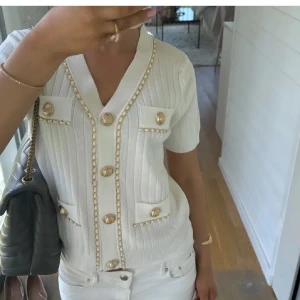 Vit ribbad kofta med guldknappar - Säljer en superfin vit ribbad kofta med korta ärmar och snygga guldknappar. Perfekt för både vardag och fest! De är en Onesize men passar xs-s💞oanvänd lånade bilder. 