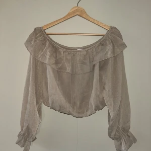 Off-shoulder croppad blus - Beige blus, off-shoulder med volang och resår i midjan. Croppad.