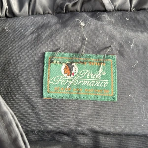 Svart jacka från Peak Performance - Säljer en svart jacka från Peak Performance. Den är perfekt för kalla dagar med sitt puffer-stil och långa ärmar. Jackan har både dragkedja och knappar för extra skydd mot kylan. Den är i bra skick och redo för nya äventyr!