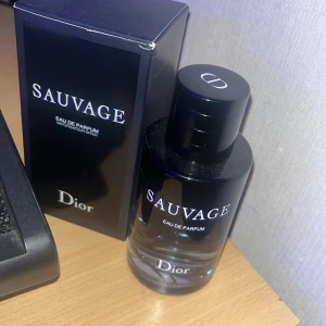 Sauvage Eau de Parfum från Dior - Säljer en flaska Sauvage Eau de Parfum från Dior. Flaskan är elegant och svart med en stilren design. Perfekt för den som vill ha en sofistikerad och maskulin doft. Kommer med originalförpackning. Passar både till vardags och fest!
