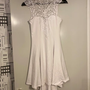 Vit klänning med spetsdetaljer - Säljer en superfin vit klänning med vackra spetsdetaljer upptill. Perfekt för sommarens alla fester eller kanske till studenten. Klänningen är i mycket bra skick.