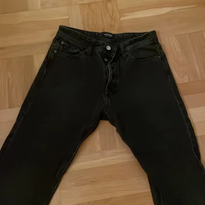 Svarta jeans från Jack & Jones - Säljer ett par svarta jeans från Jack & Jones i storlek 31/32. De har en klassisk femficksdesign och är i mycket bra skick. Perfekta för både vardag och fest! 🖤