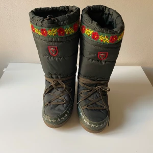 Gröna vinterstövlar från Esprit - Säljer ett par gröna vinterstövlar från Esprit med broderade blommor i rött och gult upptill. De har snörning framtill och en robust sula för bra grepp. Perfekta för kalla vinterdagar! 🥶