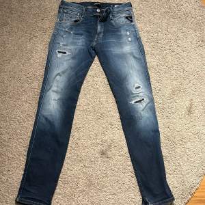 Säljer ett par snygga blå jeans från Replay med slitna detaljer. De har en slim passform. De är storlek 30 i midja och 32 längd. Passar mig är 182 väger 70