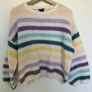 Randig stickad tröja från Lindex - Superfin stickad tröja från Lindex i storlek S. Den har ett färgglatt randigt mönster i pastellfärger som lila, grön, gul och vit. Perfekt för att liva upp garderoben! Tröjan är mjuk och bekväm med långa ärmar, perfekt för kyliga dagar.