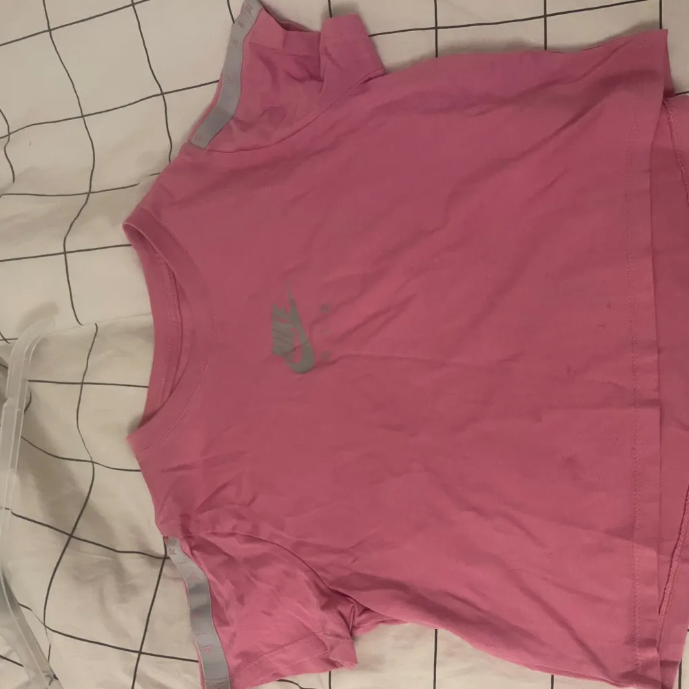 Säljer en snygg rosa t-shirt från Nike i bomull. Den har en klassisk rund hals och korta ärmar. Perfekt för träning eller vardagsbruk. Nike-loggan i grått pryder framsidan. Passar perfekt för dig som gillar sportig stil!. T-shirts.