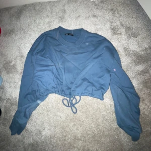 Blå croppad tröja - Säljer en snygg blå croppad tröja med långa ärmar och knytning i midjan. Perfekt för en avslappnad stil och passar bra till både jeans och kjol. Tröjan är i bra skick och redo för nya äventyr!
