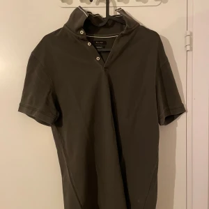 Grå pikétröja från Massimo Dutti - Säljer en stilren grå pikétröja från Massimo Dutti. Den har en klassisk krage med knappar och korta ärmar. Perfekt för både vardag och lite finare tillfällen. Tröjan är i mycket bra skick och passar perfekt till jeans eller chinos.