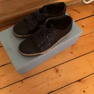 Säljer ett par svarta sneakers från Lanvin i bra skick. De har en klassisk design med snörning och en vit sula som ger en snygg kontrast. Perfekta för både vardag och festliga tillfällen. Skorna är bekväma och stilrena, ett måste i garderoben!