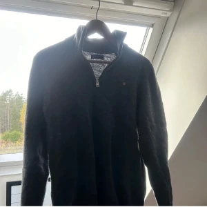 Mörkgrå tröja med dragkedja från GANT - Säljer en snygg mörkgrå tröja från GANT med halv dragkedja och broderad logga på bröstet. Perfekt för kyliga dagar och ger en stilren look. Tröjan är i bra skick och passar både till vardags och lite finare tillfällen. Storlek: M mycket bra skick: 9/10 nypris: ca 1300kr
