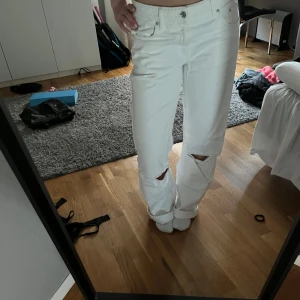Vita jeans med slitningar - Säljer ett par vita jeans i bra skick. De har en straight passform. Byxorna har coola slitningar på knäna. Jag är 167 cm.
