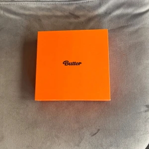BTS - 'Butter' album - Säljer BTS albumet 'Butter'. Inuti finns en CD, fotobok, fotokort och andra samlarobjekt. Perfekt för fans av kpopmusik men framförallt BTS. Lådan är i bra skick och har en stilren design.
