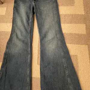 Säljer ett par snygga blå jeans med hjärtformade fickor bak. De har en bootcut-stil och är i nytt skick skick. Perfekta för en avslappnad look och passar till både vardag och fest. Jeansmaterialet är bekvämt och slitstarkt.