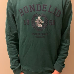 Grön sweatshirt från Bondelid - Säljer en snygg grön sweatshirt från Bondelid med tryck framtill. Tröjan har långa ärmar och är perfekt för en avslappnad stil.