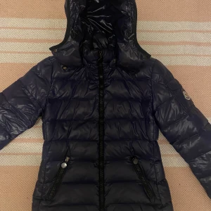 Svart dunjacka från Moncler - Säljer en snygg svart dunjacka från Moncler i mycket bra skick. Jackan har en quiltad design med dragkedja och huva, perfekt för kalla vinterdagar. Den är både stilren och varm, vilket gör den till ett måste i garderoben. Passar perfekt för vinterns alla äventyr! 🖤