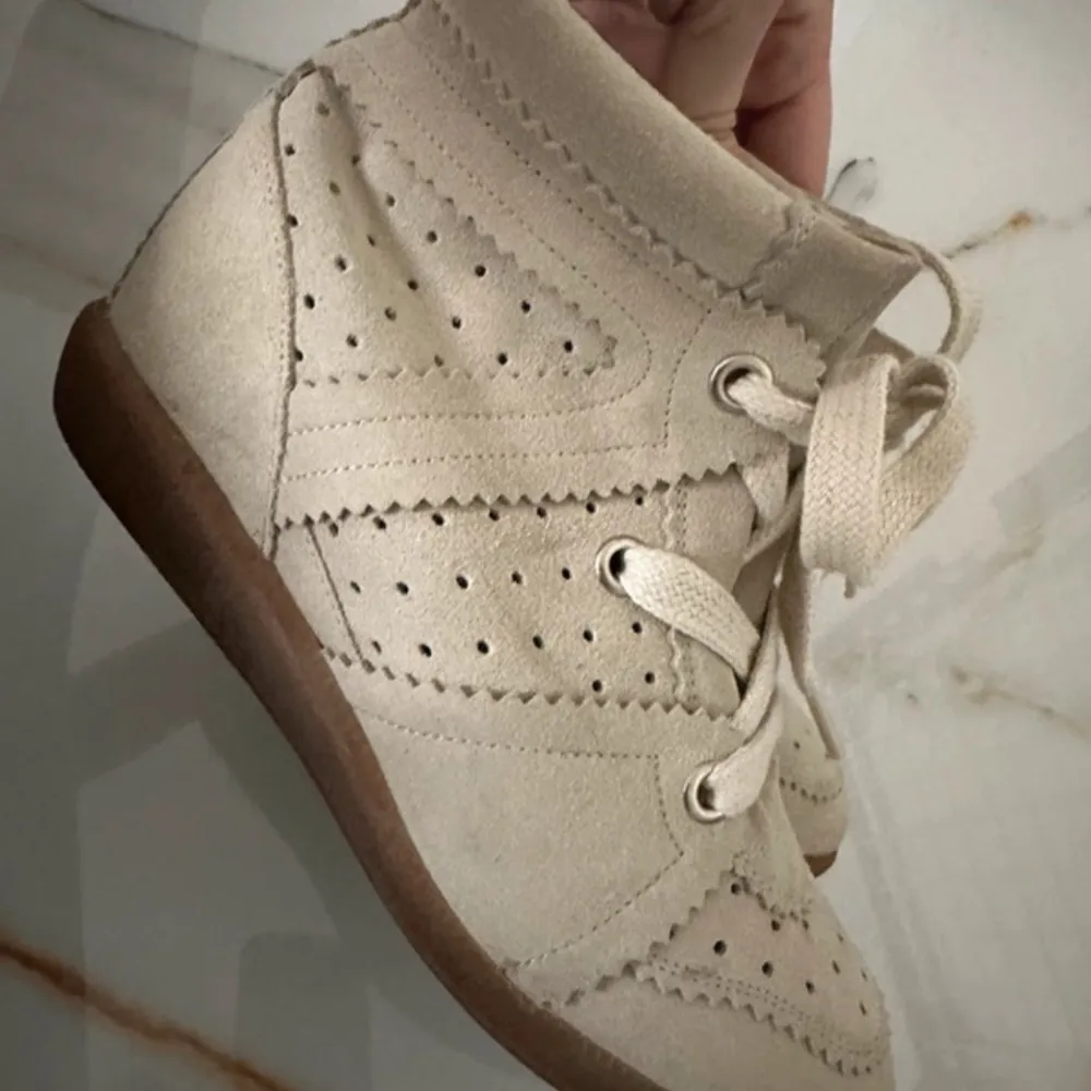 Säljer ett par snygga beige sneakers från Isabel Marant i storlek 38. Skorna har en cool perforerad design med snörning och en bekväm gummisula. Perfekta för både vardag och festliga tillfällen. De är som nya och mycket bra skick! Original pris 6000kr! Jag använt dom 2grr😊. Skor.