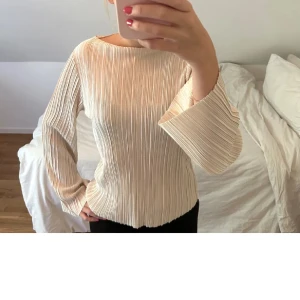 Beige plisserad blus - Säljer en superfin beige plisserad blus med långa ärmar. Perfekt för både vardag och fest! Den har en lös passform som gör den bekväm och stilren. Passar perfekt till höst och vår. 🧡