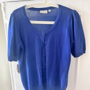 Blå kofta från Cappuccini - Säljer en superfin blå kofta från Cappuccini. Den har korta ärmar och knäpps med två knappar framtill. Perfekt för vår och sommar! 💙