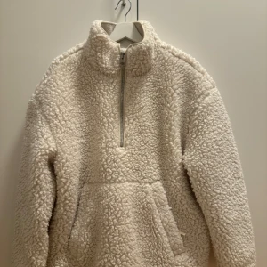 Arket Allväders jacka - Säljer en supermysig vit fleece jacka i storlek M från Arket. Den har en halv dragkedja framtill och en stor ficka för att värma händerna. Perfekt för kalla dagar när du vill känna dig som en fluffig marshmallow! 🐑