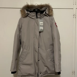 Canada goose, limestone. - Jätte fin canada goose jacka i färgen limstone, den är storlek L. Den värmer jätte bra, längden kommer till knän och den är oanvänd eftersom jag fick den i födelsedagspresent och den passar tyvärr inte mig längre. Kvitto finns, köpt från Johnells.