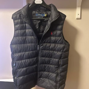 Ralph Lauren väst  - Säljer min Ralph Lauren väst nästan alldrig använd. Inga problem på den den är precis som ny vilket är najs.  100% äkta köpt på Zalando i sommras eller vintras. I storlek S passar M Jag är 182 och den passar bra 