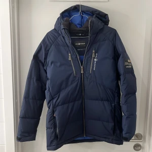 Sail Racing Jacka Marinblå - Säljer en fin Sail Racing jacka i färgen marinblå. Skicket är bra 8/10. Finns en liten fläck vid bröst dragkedjan, dock så går det förmodligen bort med en liten tvätt. Storleken är i 170 Junior. Hör gärna av dig för frågor och intresse!