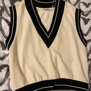 Vest - Beige och svart mjuk väst från Zara i storlek M, men med en oversized stil som även passar L-storlek. Perfekt för höstens vibbar och fungerar både för män och kvinnor. Ett mångsidigt och stiligt plagg som enkelt kan stylas för olika outfits!