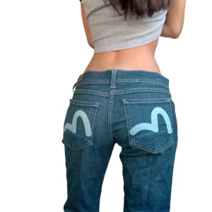 Evisu Jeans - Säljer ett par snygga blå bootcut jeans från evisuXpuma kollektionen. Innerbenslängd: 78 cm Midjemått: 80cm / Ytterbensmott 98 cm  notera att en av skärpöglorna har lossnat på en sida men går enkelt att sy tillbaka👍 Även lite slitningar längst ner på benen