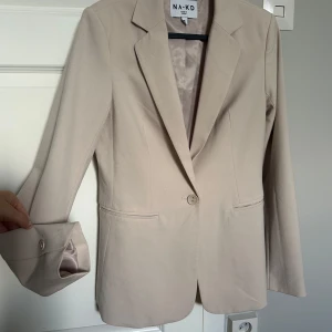 Beige kavaj - Säljer min kavaj. Aldrig använd men passar till det mesta. I fint skick och skönt material.  